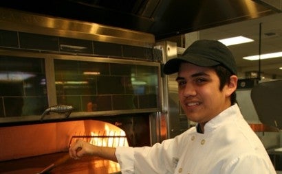 Harley Project SEARCH student putting pizza in a pizza oven